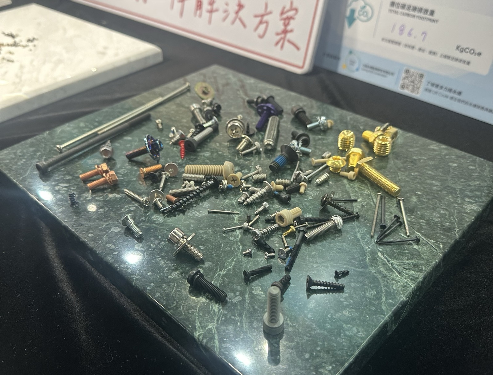 A wide spread of fasteners laid out on a marble slab: different head styles, drives, platings and diameters