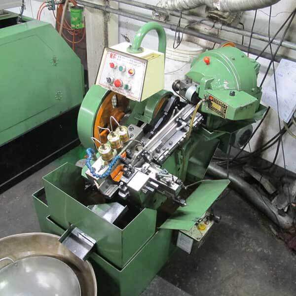 Flat die thread rolling machine, showing the reciprocating die slide and oil nozzles
